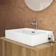 Waschtisch von Ideal Standard in seidenweiß mit rechteckiger Form und glatter Oberfläche. Armatur und Pflegeprodukte auf einer Holzablage neben dem Becken.